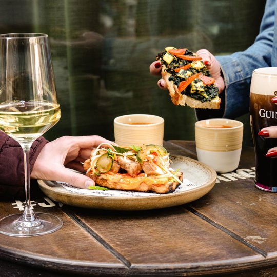 Guests enjoying open sandwiches, Guinness, and wine at Daffodil Mulligan restaurant and Irish pub in Shoreditch, London.
